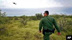 U.S. Border Patrol agent Jesus Vasavilbaso, aided by a Black Hawk helicopter, searches for a group of migrants evading capture in the desert brush at the base of the Baboquivari Mountains, Sept. 8, 2022, near Sasabe, Ariz.