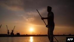 FILE - Iraqi fisherman Naim Haddad, 40, stands barefoot on his boat at sunset on Shatt al-Arab, the confluence of the Tigris and Euphrates rivers that empties into the Gulf, near the city of Basrah in southern Iraq, on Feb. 12, 2022.
