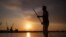 FILE - Iraqi fisherman Naim Haddad, 40, stands barefoot on his boat at sunset on Shatt al-Arab, the confluence of the Tigris and Euphrates rivers that empties into the Gulf, near the city of Basrah in southern Iraq, on Feb. 12, 2022.