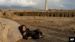 FILE - A 4-year-old Afghan girl sleeps after work in a brick factory on the outskirts of Kabul, Afghanistan, Aug. 17, 2022.