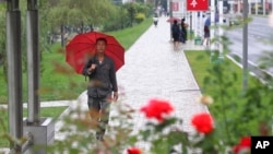 People walk after a rain in the Central District, Pyongyang, North Korea, on Sept. 14, 2022. 