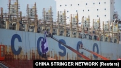 在中国山东省威海市的一个船厂，工人在一艘正在建造的中国远洋运输公司（COSCO）的船上工作（2019年5月16日）。
