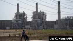 FILE - A man pushes a stroller near the AES power plant in Redondo Beach, California on September 7, 2022. (AP Photo/Jae C. Hong, File)