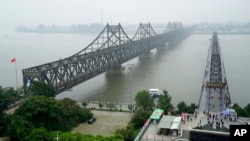 FILE - Visitors cross the Yalu River Broken Bridge, right, next to the Friendship Bridge connecting China and North Korea in Dandong China, Sept. 9, 2017. North Korea and China resumed freight train service, Sept. 26, 2022, after a five-month hiatus, South Korean officials said.
