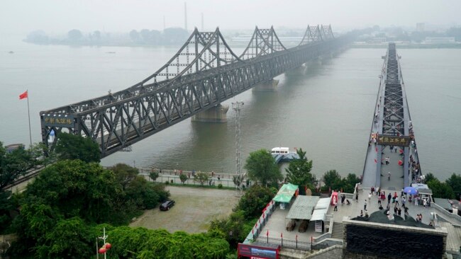 FILE - Visitors cross the Yalu River Broken Bridge, right, next to the Friendship Bridge connecting China and North Korea in Dandong China, Sept. 9, 2017. Despite an economic slowdown, China is expected to continue assisting North Korea.