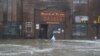 Two men walk through rushing water on Front Street, just a half block from the Bering Sea, in Nome, Alaska, Sept. 17, 2022. 