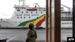 Une femme se tient devant le ferry qui naviague entre Dakar et Ziguinchor, à Ziguinchor le 24 septembre 2022.