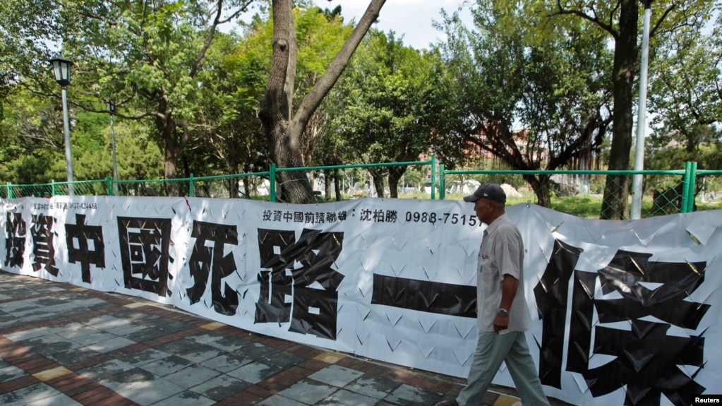 资料照：一名男子走过台北街头悬挂的写有“投资中国死路一条”字样的标语。（2012年8月8日）（路透社)