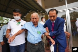 Chum Mey, center, former S21 prison survivor, is helped by court officials as he leaves the courtroom after the verdict is announced for Khieu Samphan, at the U.N.-backed war crimes tribunal in Phnom Penh, Cambodia, Sept. 22, 2022.