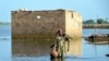 A man carries some belongings as he wades through floodwaters in Jaffarabad, a flood-hit district of Baluchistan province, Pakistan, Sept. 19, 2022. 