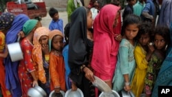 FILE - Children from flood-affected areas wait to receive food aid, in Lal Bagh, Sindh province, Pakistan, Sept. 13, 2022.