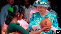 FILE- An Indian woman presents Britain's Queen Elizabeth II with an earthenware pot prepared by her at St Francis Church in the Indian port city of Cochin, Oct. 17, 1997.