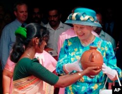 ARCHIVO- Una mujer india le presenta a la reina Isabel II de Gran Bretaña una vasija de barro preparada por ella en la iglesia de San Francisco en la ciudad portuaria india de Cochin, el 17 de octubre de 1997. (AP Photo/Sherwin Crasto, File)
