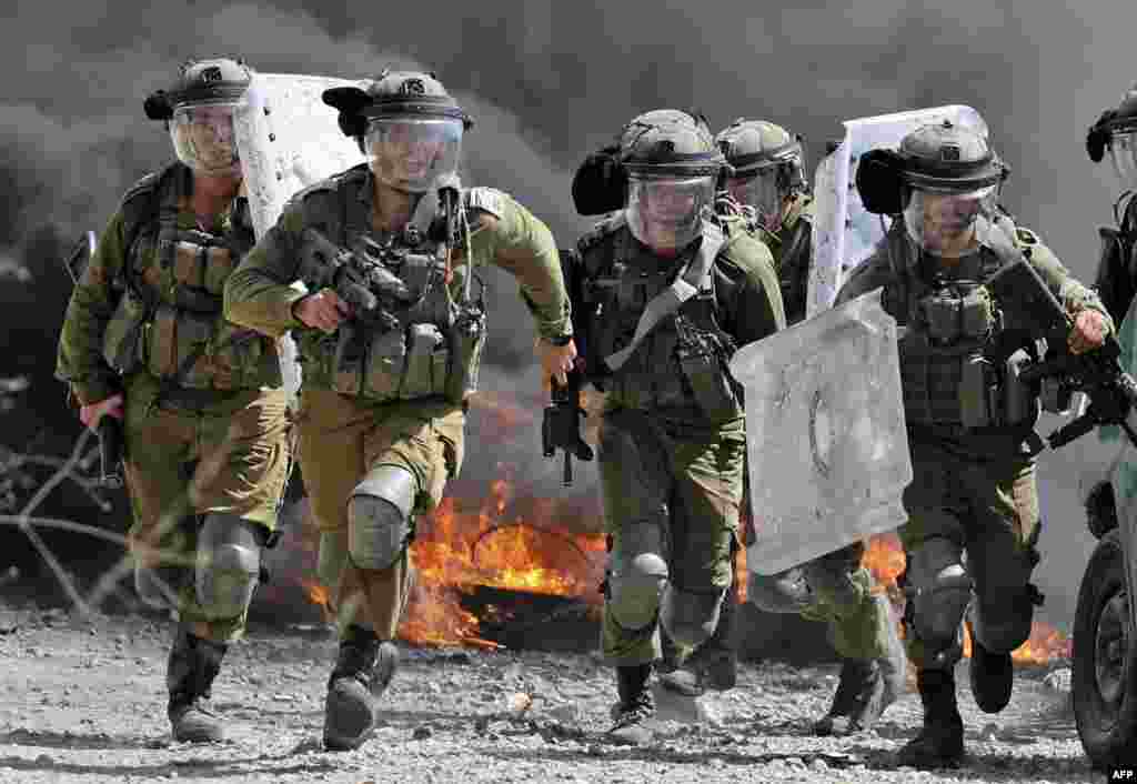 Israeli security forces run towards Palestinian demonstrators during clashes following a protest against the expropriation of Palestinian land by Israel in the village of Kfar Qaddum in the occupied West Bank near the Jewish settlement of Kedumim.