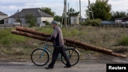 A man carries wood, which he says is collected from abandoned Russian military bunkers, on his bicycle to use for heating during the winter, as Russia's attack on Ukraine continues, in the town of Izium, Kharkiv region, Sept. 20, 2022. 