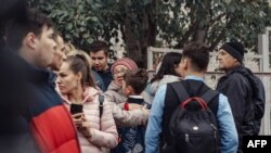 A woman hugs a boy surrounded by other people near the scene of a shooting at a school in Izhevsk, Russia, Sept. 26, 2022.