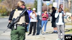 Una oficial de policía fuertemente armada establece el perímetro alrededor del sitio del tiroteo en San Bernardino, California.