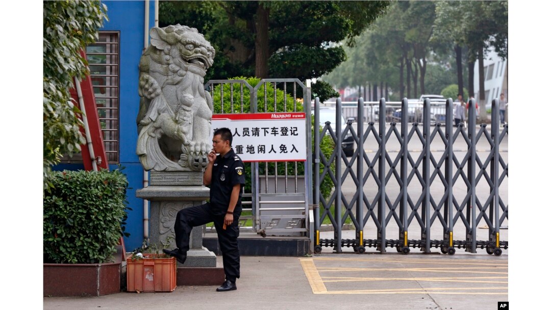 A security guard smokes near a main entrance gate of the Ganzhou Huajian International Shoe City Co.'s factory, which has made shoes for the Ivanka Trump brand, in Ganzhou in southern China's Jiangxi province, June 18, 2017. The sign instructs visitors to "please exit the vehicle and register. People without relevant reasons cannot enter this important factory area."