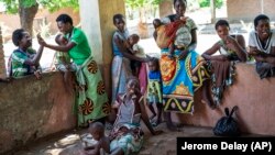 In this file photo taken on December 11, 2019, locals of the Malawi village of Tomali wait to have their young children become test subjects for the world's first vaccine against malaria. (AP Photo/Jerome Delay)