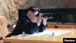 Une photo publiée par l‘agence de presse coréenne KCNA montre le leader de la Corée du Nord suivant, à travers ses jumelles, le test du missile inter-continental Hwasong-14 à Pyongyang, le 4 juillet 2017.