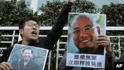 FILE - Pro-democracy activists hold pictures of Chinese activists Wu Gan, right, and Qin Yongmin outside the Chinese central government's liaison office in Hong Kong, Dec. 27, 2017.