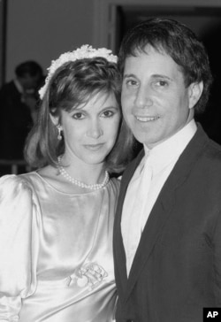 FILE - Actress Carrie Fisher and singer Paul Simon pose in a doorway of the midtown New York City apartment where their wedding reception was in progress, Aug. 16, 1983.