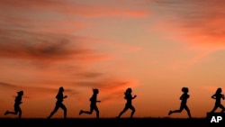 FILE - High school students run at sunset as they practice for the track and field season Monday, Feb. 28, 2022, in Shawnee, Kan. New research hints that even simple exercise just might help fend off memory problems. (AP Photo/Charlie Riedel, File)