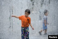 上海酷暑中小朋友在喷水池中冲凉。（2022年7月22日）