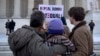 FILE - In this March 27, 2013, file photo a protester holds up a sign that reads "REPEAL DOMA," the Defense of Marriage Act in front of a group from Alabama, clasped in prayer in front of the Supreme Court in Washington, as the court hears arguments on gay marriage. 