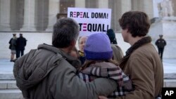 FILE - In this March 27, 2013, file photo a protester holds up a sign that reads "REPEAL DOMA," the Defense of Marriage Act in front of a group from Alabama, clasped in prayer in front of the Supreme Court in Washington, as the court hears arguments on gay marriage. 