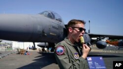 FILE: A member of the military personnel eats an ice cream as he stands past an F15E Strike Eagle fighter jet, on display at the Farnborough Air Show fair in Farnborough, England, July 19, 2022.