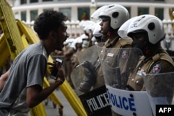 A demonstrator interacts with police special task force personnel standing guard while blocking a road during in a protest march against Sri Lankan President Ranil Wickremesinghe towards the Presidential secretariat office in Colombo, Sri Lanka.