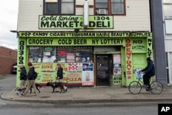 Orang-orang berjalan dengan anjing dan bersepeda di dekat Cold Spring Market & Deli di Jefferson Avenue, Buffalo, New York, Selasa, 17 Mei 2022. (AP/Joshua Bessex)