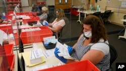 FILE — Election workers inspect ballots that have been received for the Sept. 14, recall election, for damage at the Sacramento County Registrar of Voters office in Sacramento, California, Aug. 30, 2021. 