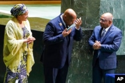 Morissanda Kouyate, Minister of Foreign Affairs of the Republic of Guinea, center, kisses the United Nations Nelson Rolihlahla Mandela Prize presented to him at the U.N. General Assembly during its annual celebration of Nelson Mandela International Day, at United Nations headquarters, July 18, 2022.