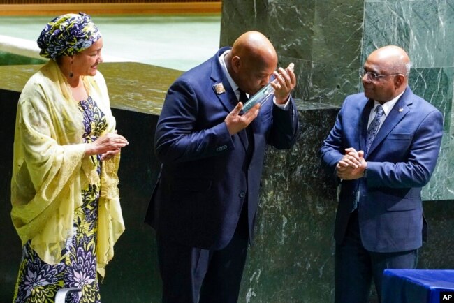 Morissanda Kouyate, Minister of Foreign Affairs of the Republic of Guinea, center, kisses the United Nations Nelson Rolihlahla Mandela Prize presented to him at the U.N. General Assembly during its annual celebration of Nelson Mandela International Day, at United Nations headquarters, July 18, 2022.