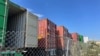 FILE - Containers stored on a lot are seen among warehouses in Fontana, California, July 17, 2022.