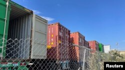 FILE - Containers stored on a lot are seen among warehouses in Fontana, California, July 17, 2022.