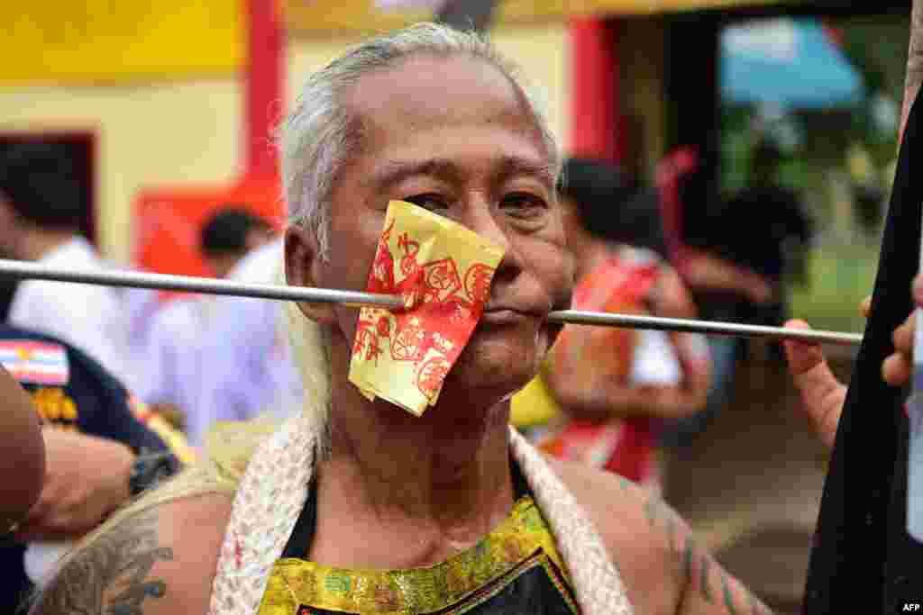 A man looks on after having his cheeks impaled as he takes part in yearly event in honor of the goddess of the Gow Lengchi Shrine, a shrine in Narathiwat town, in Thailand&#39;s southern Narathiwat province.