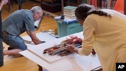 Leola One Feather, right, of the Oglala Sioux Tribe in South Dakota, lines up a grouping as John Willis photographs, left, Native American artifacts on July 19, 2022, at the Founders Museum in Barre, Massachusetts. 