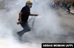 Seorang pelajar Palestina lari menghindari gas air mata saat bentrok dengan pasukan keamanan Israel di pintu masuk utara Kota Ramallah, Tepi Barat, 6 Agustus 2022. (Foto: AFP)
