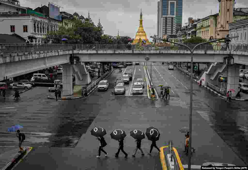 Protesters walk through a road in Yangon, Myanmar, with umbrellas bearing the number 8 in Burmese during a rally to mark the anniversary of the August 8, 1988 democracy uprising. 