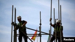 Trabajadores construyen una estructura de tubería en un andamio durante el Día Mundial de la Seguridad y la Salud en el Trabajo en la capital andaluza de Sevilla, sur de España, el 28 de abril de 2016. REUTERS/Marcelo del Pozo/Foto de archivo