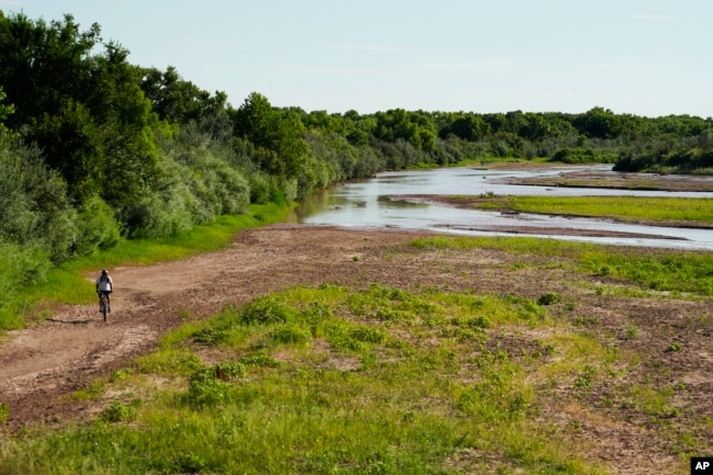 A cyclist bikes through a mostly dry Rio Grande riverbed Wednesday, July 27, 2022, in Albuquerque, N.M. AP Photo/Brittany Peterson)