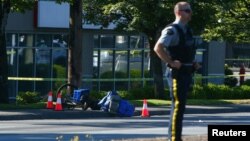 A police officer stands near a bicycle lying on the ground after authorities alerted residents of multiple shootings targeting transient victims in the Vancouver suburb of Langley, British Columbia, Canada July 25, 2022. 