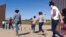 FILE - Brazilian migrants make their way around a gap in the U.S.-Mexico border in Yuma, Ariz., seeking asylum in the U.S. after crossing over from Mexico, June 8, 2021. 