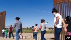 ARCHIVO - Migrantes brasileños se abren camino alrededor de una brecha en la frontera entre Estados Unidos y México en Yuma, Arizona, en busca de asilo en Estados Unidos después de cruzar desde México, el 8 de junio de 2021.