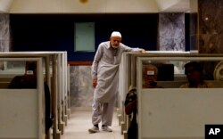 FILE - An investor monitors a stock index on a screen while brokers work at their desks at the Pakistan Stock Exchange, which responded positively after the news of an International Monetary Fund bailout package, in Karachi, Pakistan, July 14, 2022.