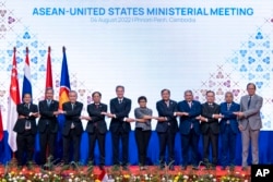 Officials do the "ASEAN-way handshake" for a group photo at the Sokha Hotel in Phnom Penh, Cambodia, Aug. 4, 2022.