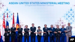 Officials do the "ASEAN-way handshake" for a group photo at the Sokha Hotel in Phnom Penh, Cambodia, Aug. 4, 2022